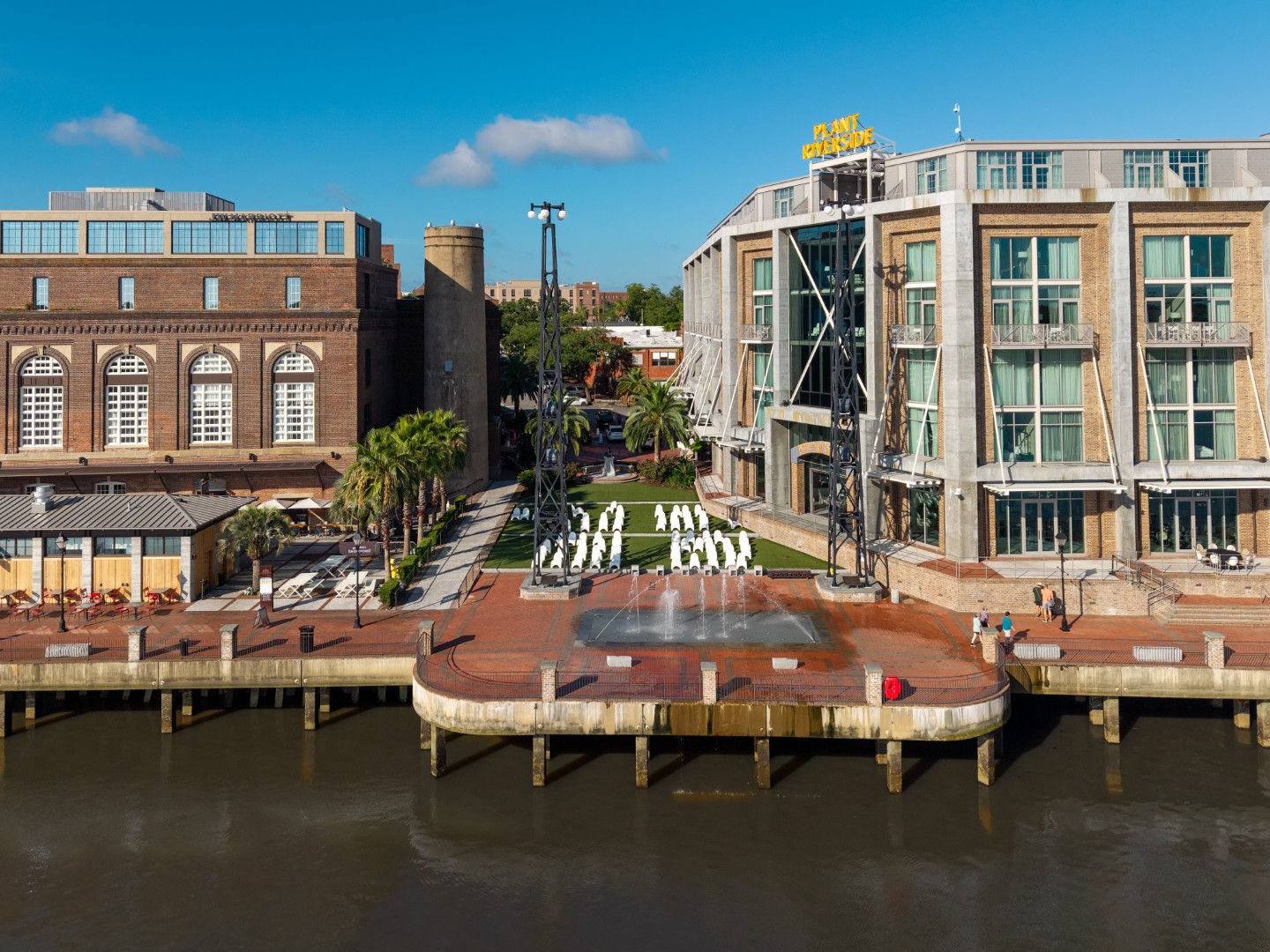 A riverside plaza in front of modern brick buildings.