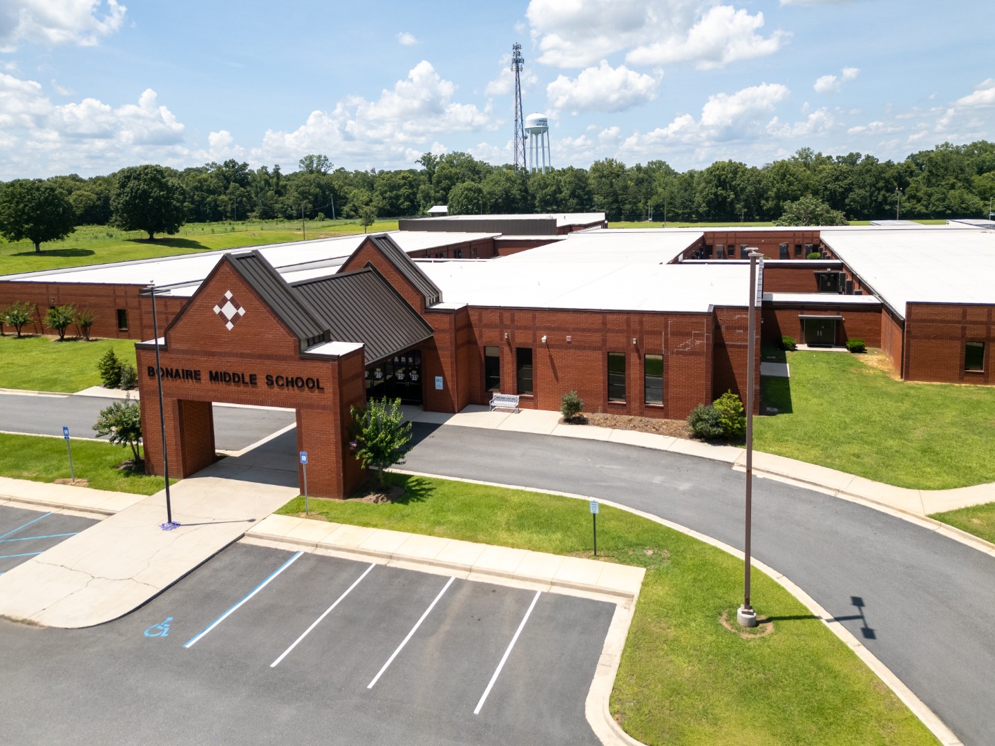 Aerial view of a red-brick middle school building with Bonaire Middle School on the entrance, surrounded by green lawns, trees.